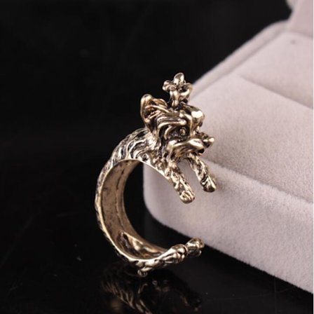 Ring med terrier hund, der krammer finger guld, sølv og sort