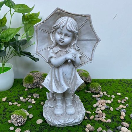 Steinfigur av liten jente i hagen med solcelledrevet paraply