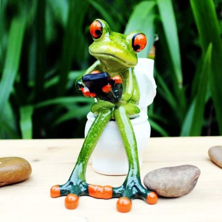 Groda Figur Dekoration, En Groda Sitter På Toaletten Och Spelar Med Sin Telefon