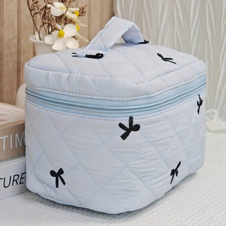 En smuk quiltet makeup taske med en enkelt broderet sløjfe, perfekt til damer. Denne bærbare rejsetaske tilbyder rigelig opbevaringskapacitet og 